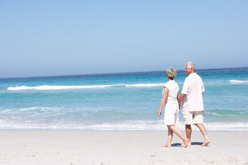 Senior Couple On Holiday Running Along Sandy Beach