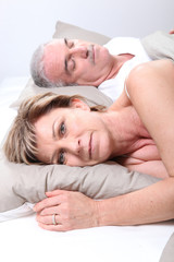 Fototapeta na wymiar Couple de seniors allongés dans un lit