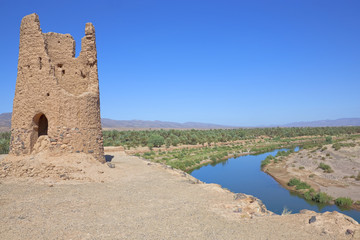 Clay ruin with date palm oasis and river