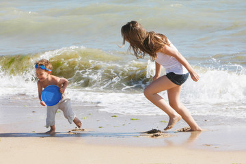 Fototapeta premium mother and son playing frisbee on beach