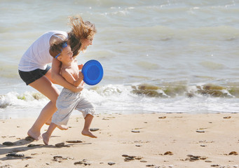 mother and son playing frisbee on beach