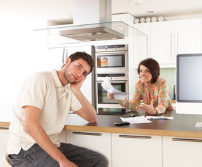 Naklejka na ściany i meble Young Couple Discussing Personal Finances In Modern Kitchen