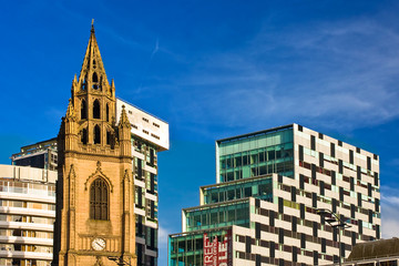 Contrast of modern office building and old church tower