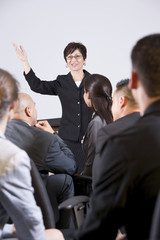 Hispanic woman speaking to group of businesspeople