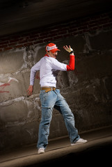 Obraz na płótnie Canvas Hip hop boy dancing in modern style over grey brick wall