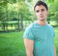 Portrait of a handsome young man while outdoors in a park on a l