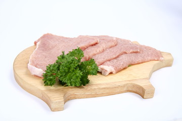 Raw tenderized pork chops on a pig shaped chopping board