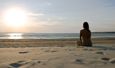 Young girl sitting on a deserted beach