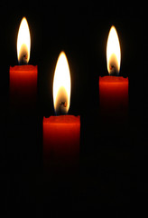 Three blazing candles on a black background