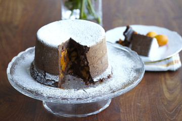 Steamed chocolate pudding cake with kumquats and dusting sugar