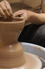 potter's wheel and hands of craftsman hold a jug
