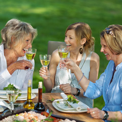 drei frauen mit wein im garten