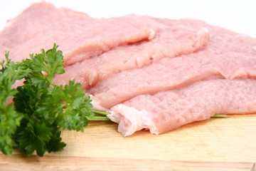 Raw tenderized pork chops on a chopping board
