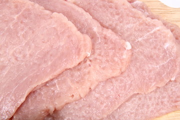Raw tenderized pork chops on a chopping board in close up