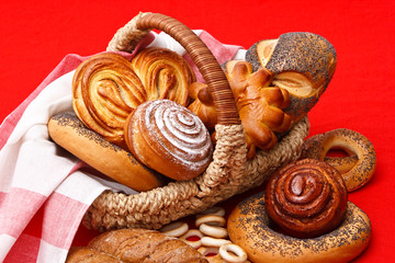 Assortment of baked bread in basket on red background