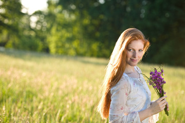 Fototapeta na wymiar Long red hair woman in romantic sunset meadow