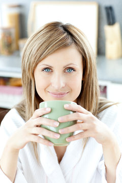 Cheerful woman holding a cup of coffee in the kitchen
