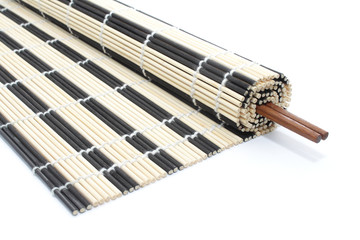 Obraz premium Half-rolled bamboo mat with chopsticks on white