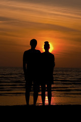 Couple watching the sunset (silhouette) hugging