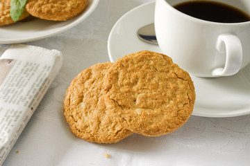 Two brown wholemeal biscuits with a white cup and saucer