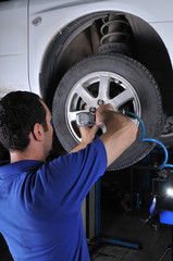 Car mechanic removing wheel nuts to check brakes