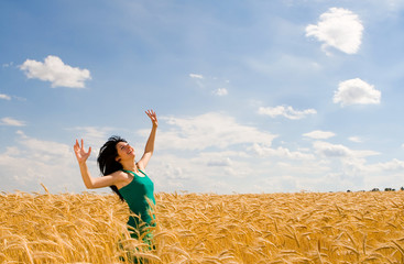 Happy woman jumping in golden wheat