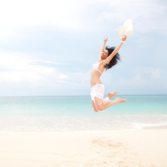 happy young woman jumping in the beach