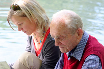 Großvater und Enkelin beim Zeitunglesen im Grünen am Teich