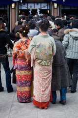 Japanese women in kimono wait to pray at a shrine