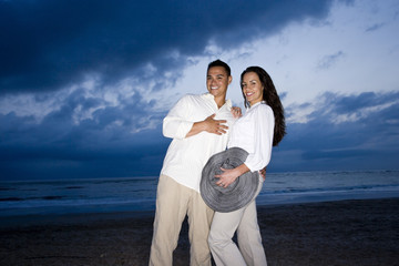 Mid-adult Hispanic couple smiling on beach at dawn