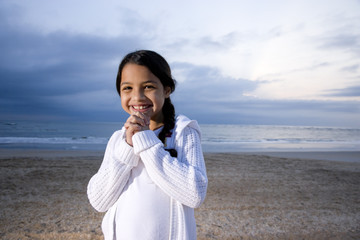 Cute little Hispanic girl smiling on beach at dawn