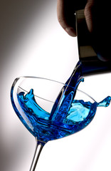 Pour blue liquid into a cocktail glass