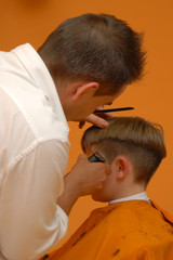 Fototapeta premium peluquero cortando el pelo a niño en peluqueria