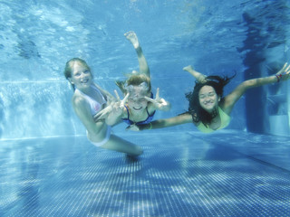 Drei Mädchen tauchen fröhlich im Pool - obrazy, fototapety, plakaty