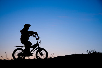 Obraz na płótnie Canvas Silhouette of boy on bike