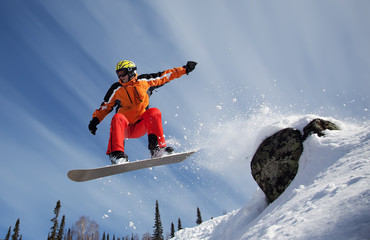 Snowboarder jumping through air with  blue sky in background
