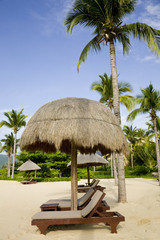 Thatched sunshade and chaise longue in summer resort