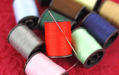Several spools of thread with a sewing needle