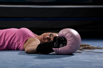 Blonde girl lying knocked out in a boxing ring