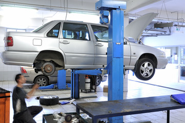 Auto mechanic changing tire under the car.