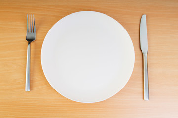Plate with utensils on wooden table