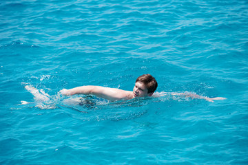 young man swims in the sea.