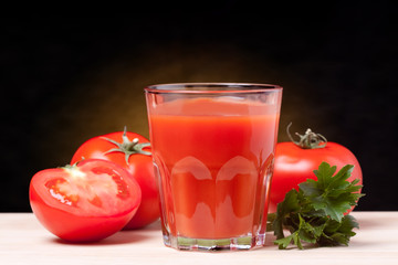 Fresh tomatoes and a glass full of tomato juice.