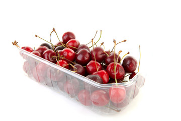 plastic container with cherries over white background