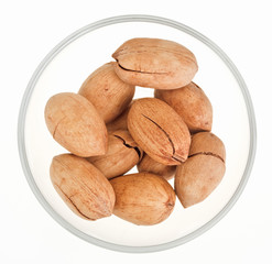 Pecan nuts in a glass bowl isolated on white