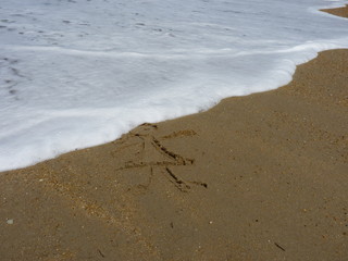 enfant dessiné sur le sable d'une plage