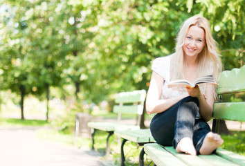 Obraz premium young woman reading book in park