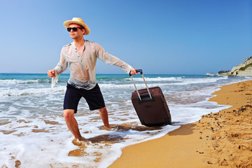 A tourist carrying a suitcase at the beach at Corfu island