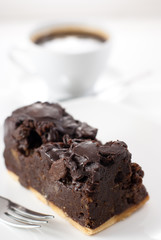 Delicious dark chocolate cake with coffee in background