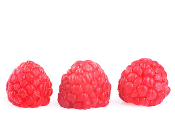 Three raspberries in a row on white